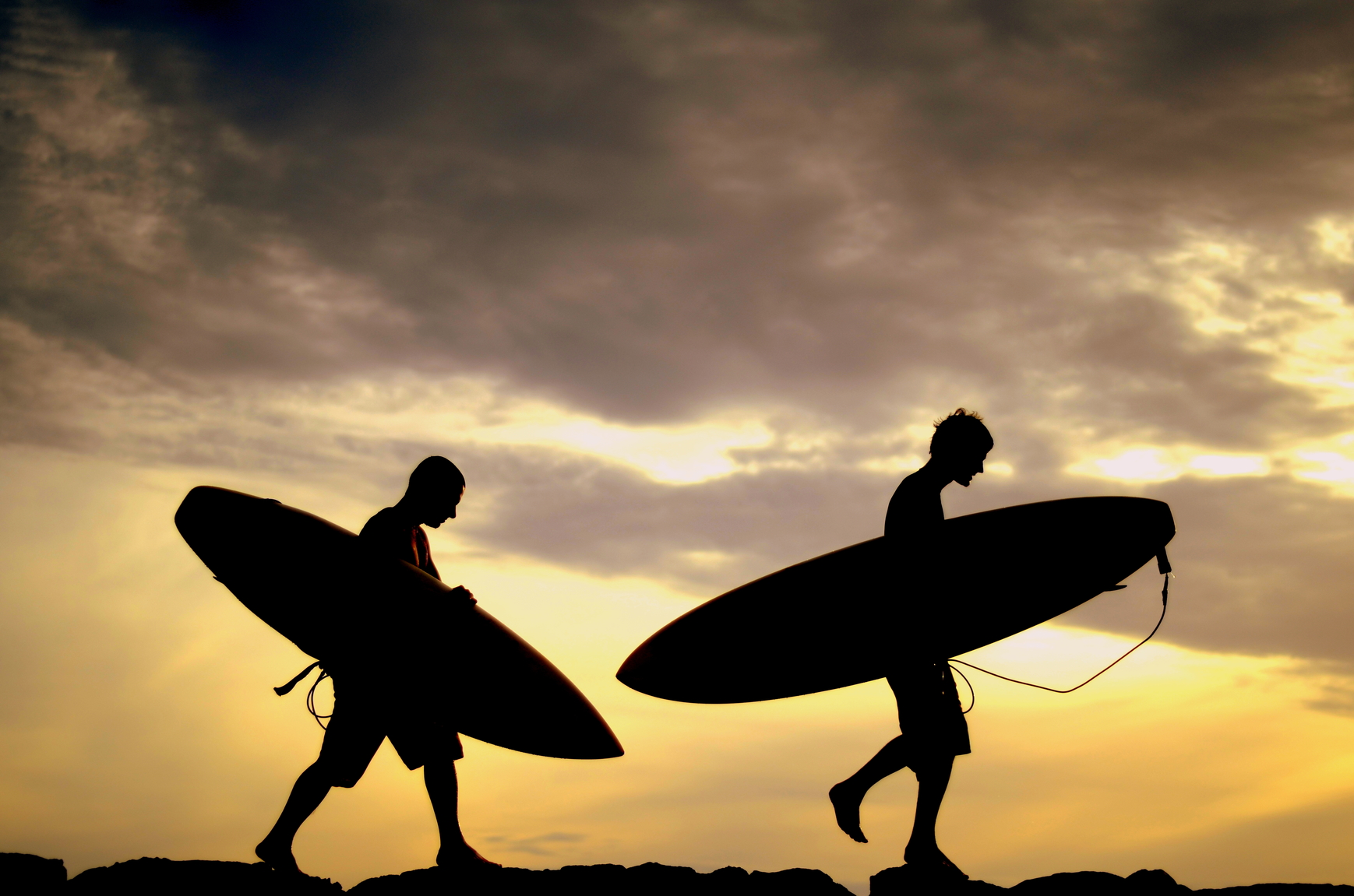 Vacation Silhouette Of Two Surfers Carrying Their Boards Home At Sunset
